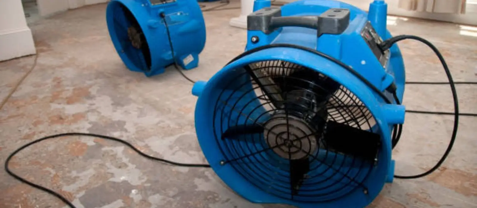 Blue air mover running on a floor after water damage