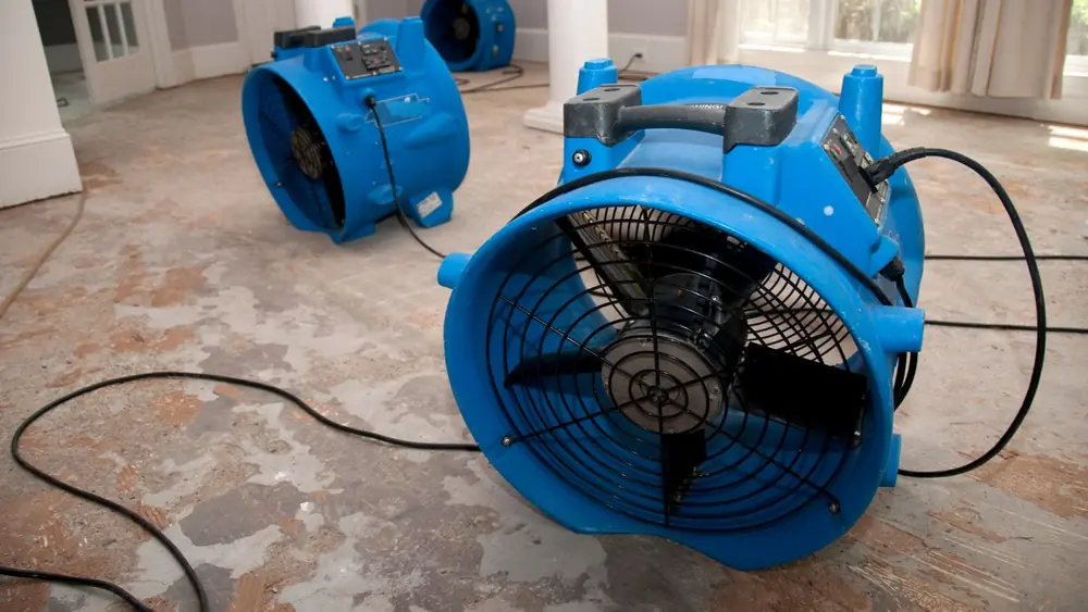 Blue air mover running on a floor after flooding
